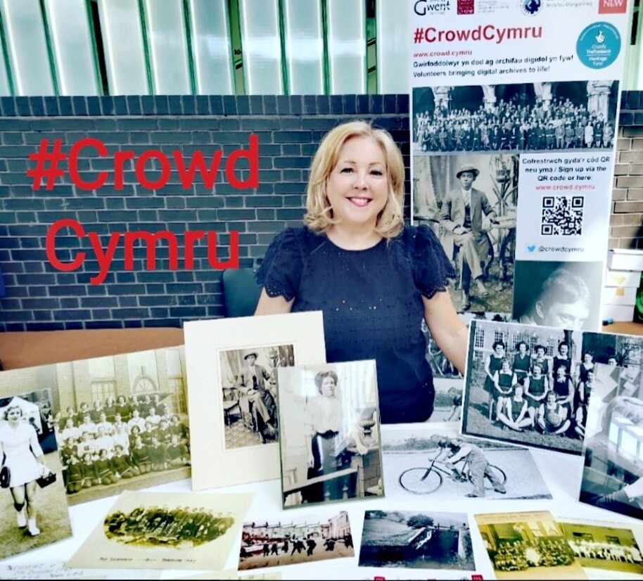 Swyddog Prosiect Jen Evans yn sefyll tu ol i bwrdd gyda ffotograffiau a delweddau o'r prosiect