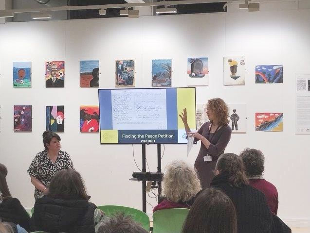 Staff Archifau Conwy yn cyflwyno ar y prosiect i gynulleidfa sy'n eistedd