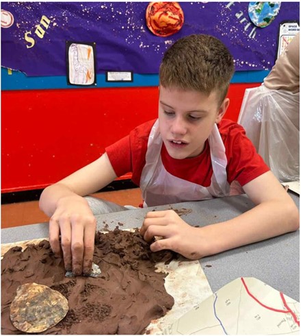 person ifanc yn defnyddio clai i greu