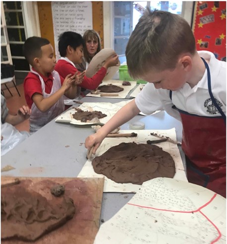 person ifanc yn defnyddio clai i greu