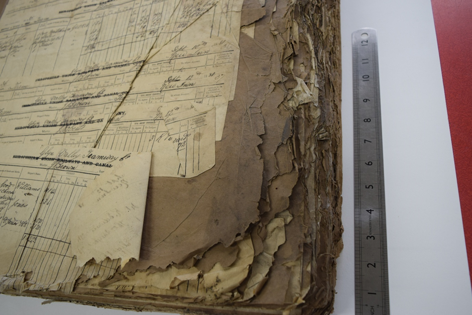 Yn y llun mae dogfen hen wedi;i ddifrodi, gyda tudalennau wedi'u gwasgu i'w gilydd.